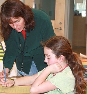 Melissa Stewart working with a student during a school visit