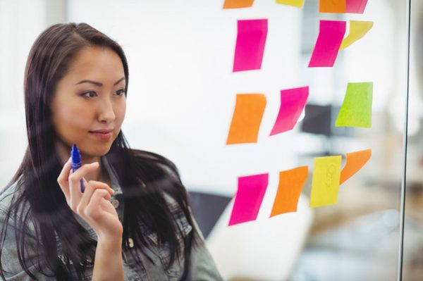 young woman writing using sticky notes to arrange ideas
